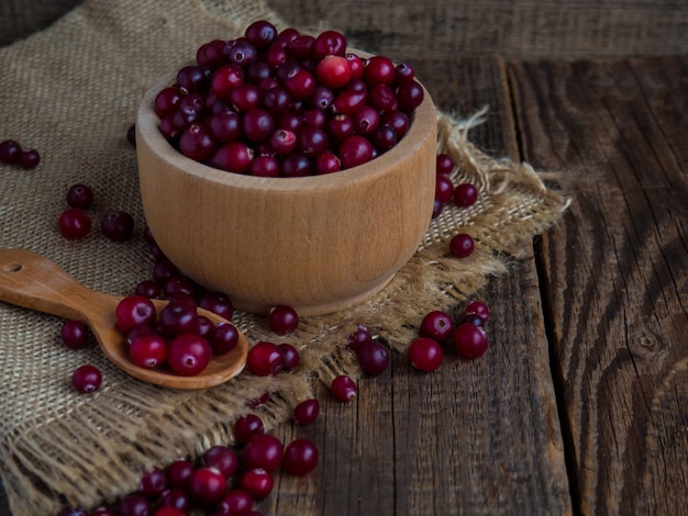 Ripe fresh cranberries in a wooden bowl on a rustic table top.