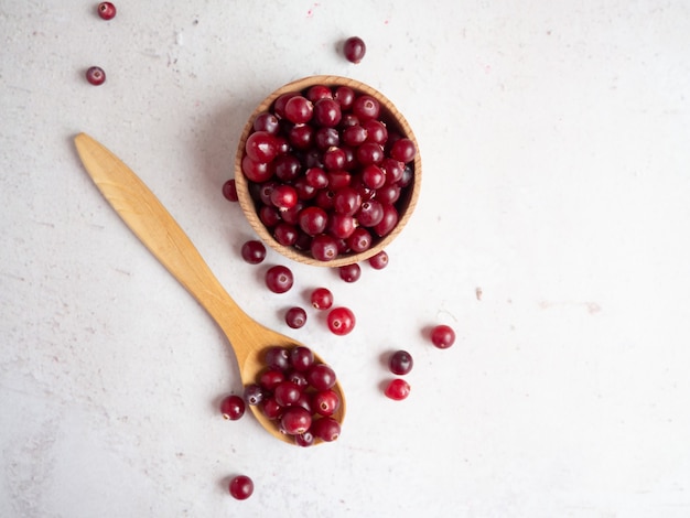 Ripe fresh cranberries in wooden bowl and wooden spoon on concrete table top with copy space