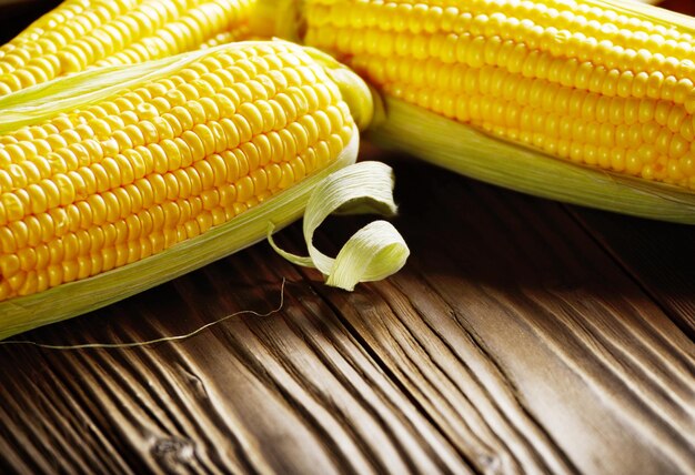 Ripe fresh organic sweet corncobs on wooden table