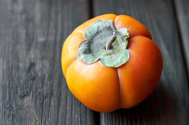 Ripe fresh persimmon on brown wooden table