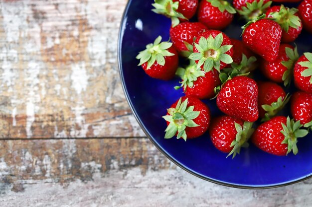 Ripe fresh strawberries on a blue plate.