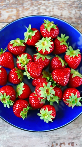 Ripe fresh strawberries on a blue plate.