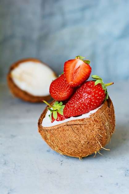 Ripe fresh strawberries in half of coconut on a blue background