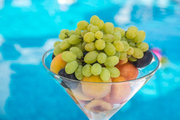 Foto frutta matura in un vaso di vetro vicino alla piscina