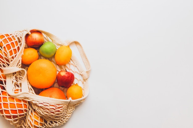 Photo ripe fruits in the crochet net bag on the white space. healthy life style concept. delivery concept.