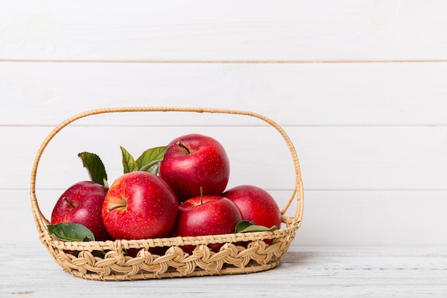 Ripe garden apple fruits with leaves in basket on wooden table Top view flat lay with copy space