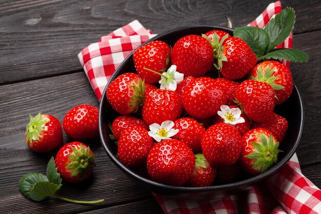 Ripe garden strawberry in bowl on wooden table