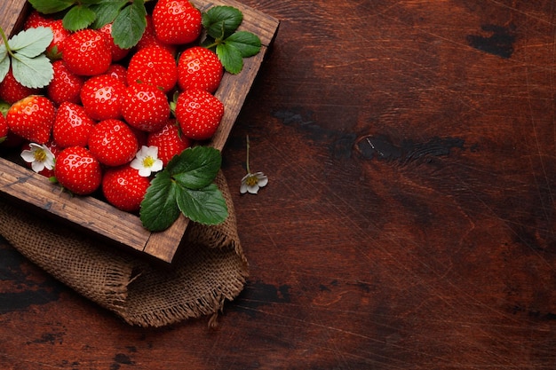 Ripe garden strawberry in box on wooden table Top view flat lay with copy space