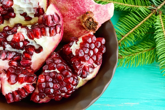 Ripe garnet have broken into pieces in a clay bowl. Juicy Asian fruit. Close-up.