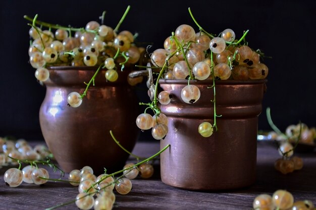 Ripe golden currant berries in a metalic vintage jars. front\
view