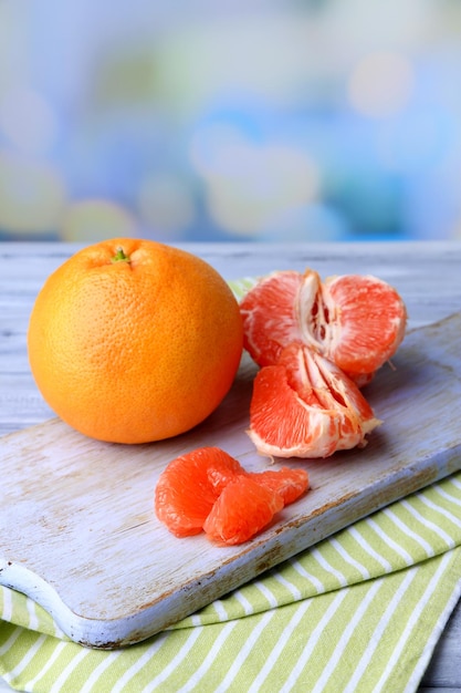 Ripe grapefruits on cutting board on wooden background