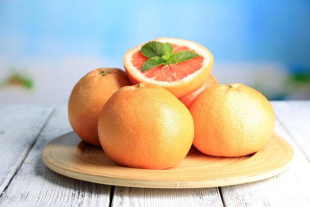 Ripe grapefruits on wooden board on bright background