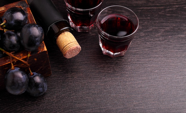 Ripe grapes, red wine and a glass on a black background