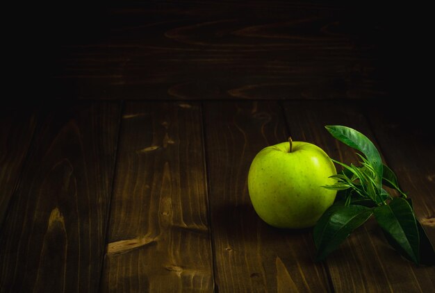 Ripe green apple on a wooden table on a dark background