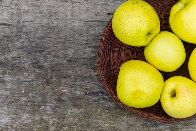 Ripe green apples in a basket on rustic wooden table. Top view