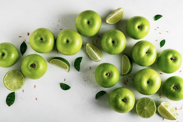 Ripe green apples and juicy limes on a light background