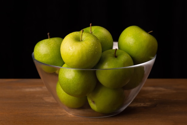 Ripe green apples in a transparent bowl