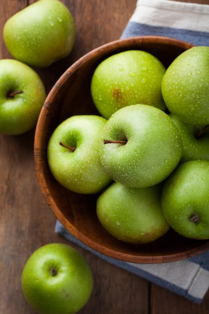 Ripe green apples in a wooden bowl.