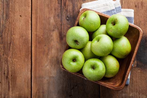 Ripe green apples in a wooden bowl.