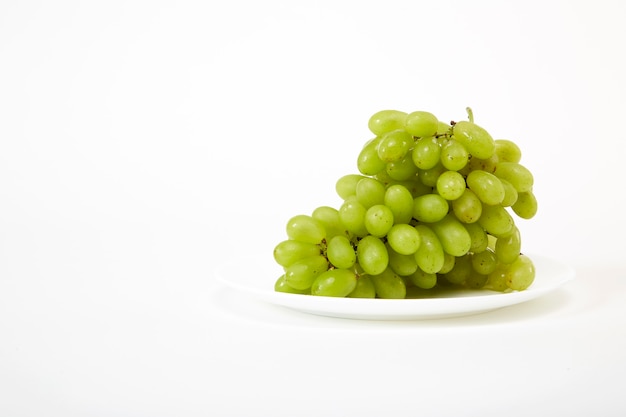 Ripe green grapes on a white plate    