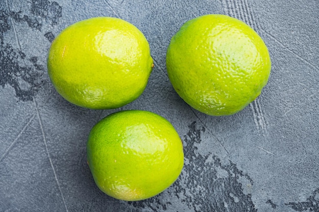 Photo ripe green lime set, on gray background, top view or flat lay