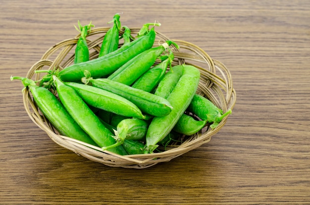 Ripe green peas pods on wooden background. 