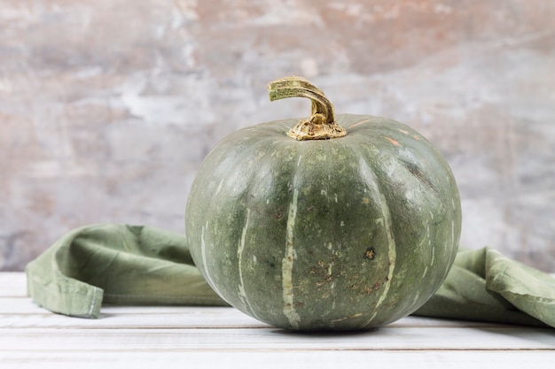 Ripe green pumpkin on a white wooden table. Blurred background