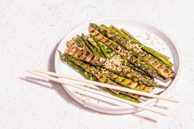 Ripe grilled asparagus. Golden flax seeds, healthy and wholesome food concept. Modern hard light, dark shadow. Light putty background, copy space