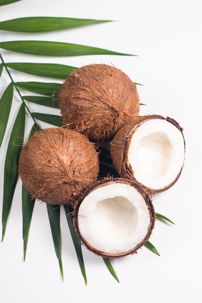 Ripe half cut coconut with green leaves on a white background. Isolated concept.