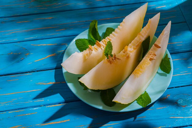 Photo ripe juicy appetizing melon on a blue table on a hot summer day. light organic snack, vegetarian dessert, healthy food