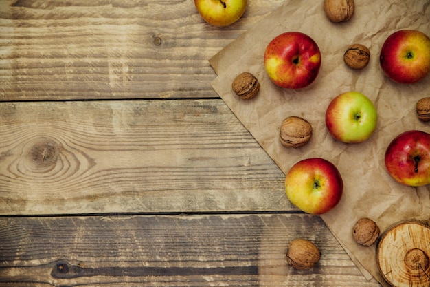잘 익은 즙이 많은 사과와 호두는 나무 배경에 놓여 있습니다. 건강한 과일입니다. 채식주의. 건강한 식생활과 다이어트.