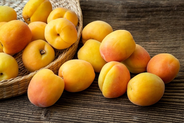 Ripe juicy apricots in a basket on a wooden background