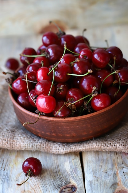 Ripe juicy cherries in a bowl on a wooden surface