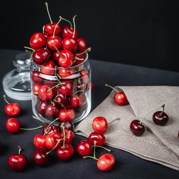 Ripe juicy cherries in a glass on dark