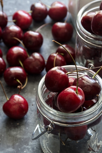 Ripe and juicy cherries on table in jars, dark background.