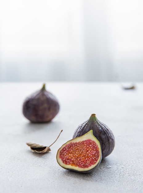 Ripe juicy figs and half  on a white table near the window. Morning light. Macro and close up view, copy space

