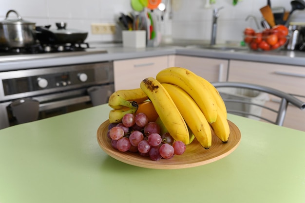 ripe juicy fruits in a wooden plate stand on the kitchen table