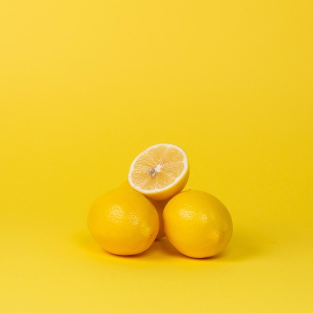 Ripe juicy lemons orange and green leaves on bright yellow background Lemon fruit citrus minimal concept vitamin C Creative summer minimalistic background Flat lay top view copy space