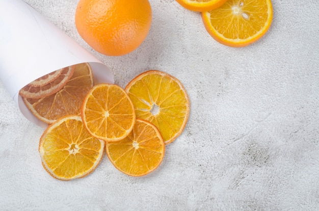 Ripe juicy oranges on grey background and dried orange chips around. Fruit chips. Healthy eating concept, snack, no sugar. Top view, copy space.