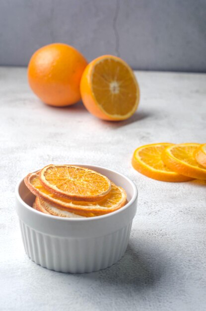 Ripe juicy oranges on grey background and dried orange chips around. Fruit chips. Healthy eating concept, snack, no sugar. Top view, copy space.