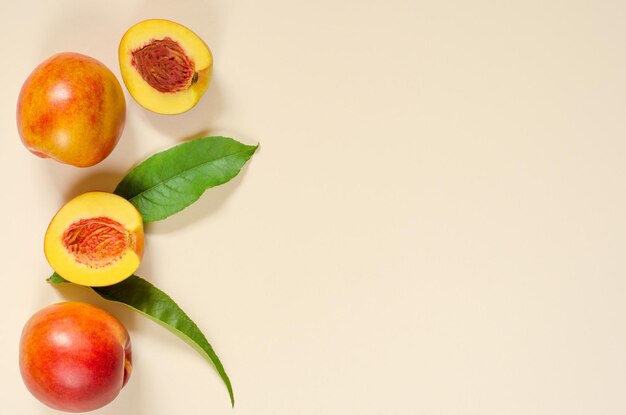 Ripe juicy peaches and green leaves on a light background with place for text