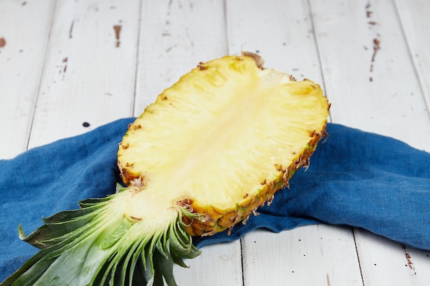 Ananas maturo e succoso su una tavola di legno bianca mezzo fette di ananas primo piano