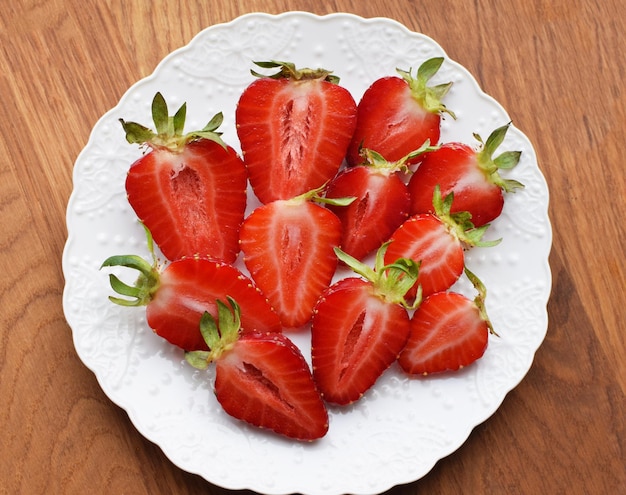 Ripe juicy strawberries cut in halves on a white plate