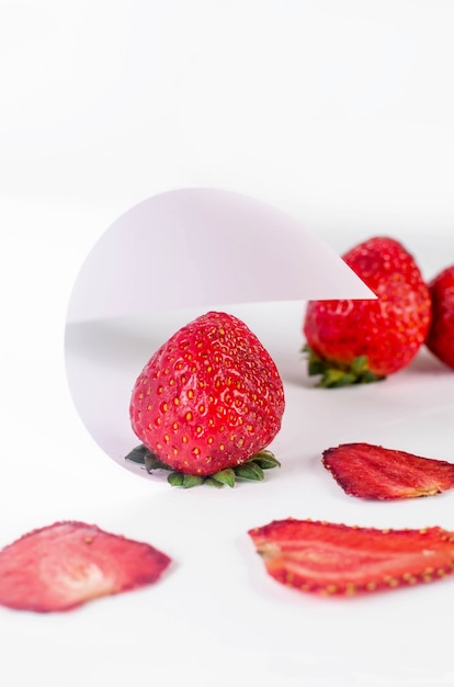 Ripe juicy strawberry with dried chips scattered on abstract white background