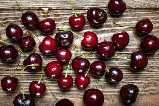 Ripe juicy sweet cherries on a wooden background top view wet\
fresh cherries with water drops