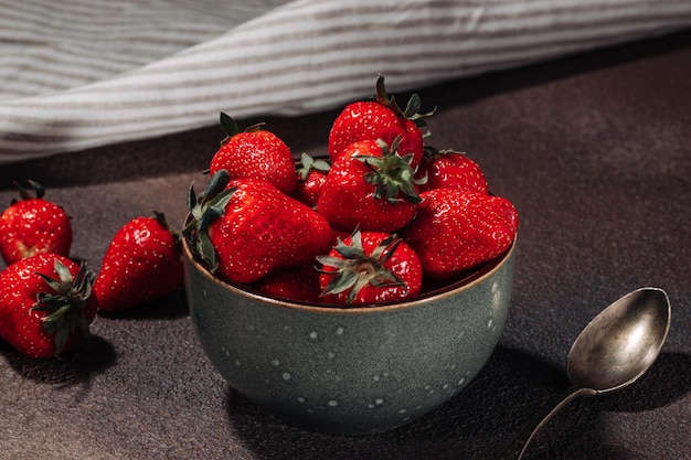 Ripe juicy tasty strawberries in a bowl on a brown background