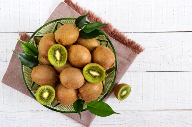 Ripe kiwi fruit in a bowl on a white wooden background