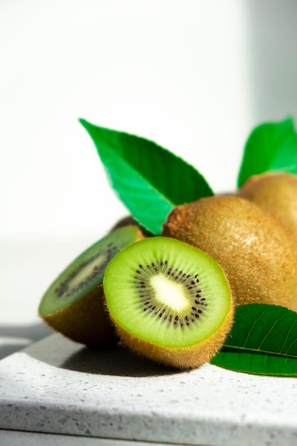 Ripe kiwi fruits in sunlight Heap of whole kiwi fruits with green leaves and fresh cut kiwi on table Healthy organic fruits full of vitamins and antioxidants