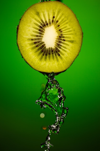 Ripe kiwifruit with drops of water isolated on green background