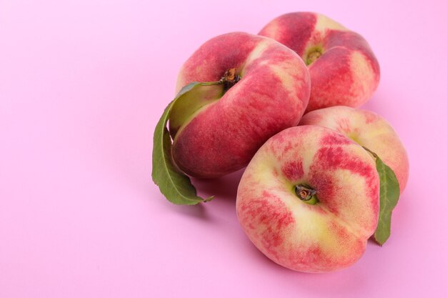 Ripe large fig figs peach with a green leaf close-up on a bright paper pink background